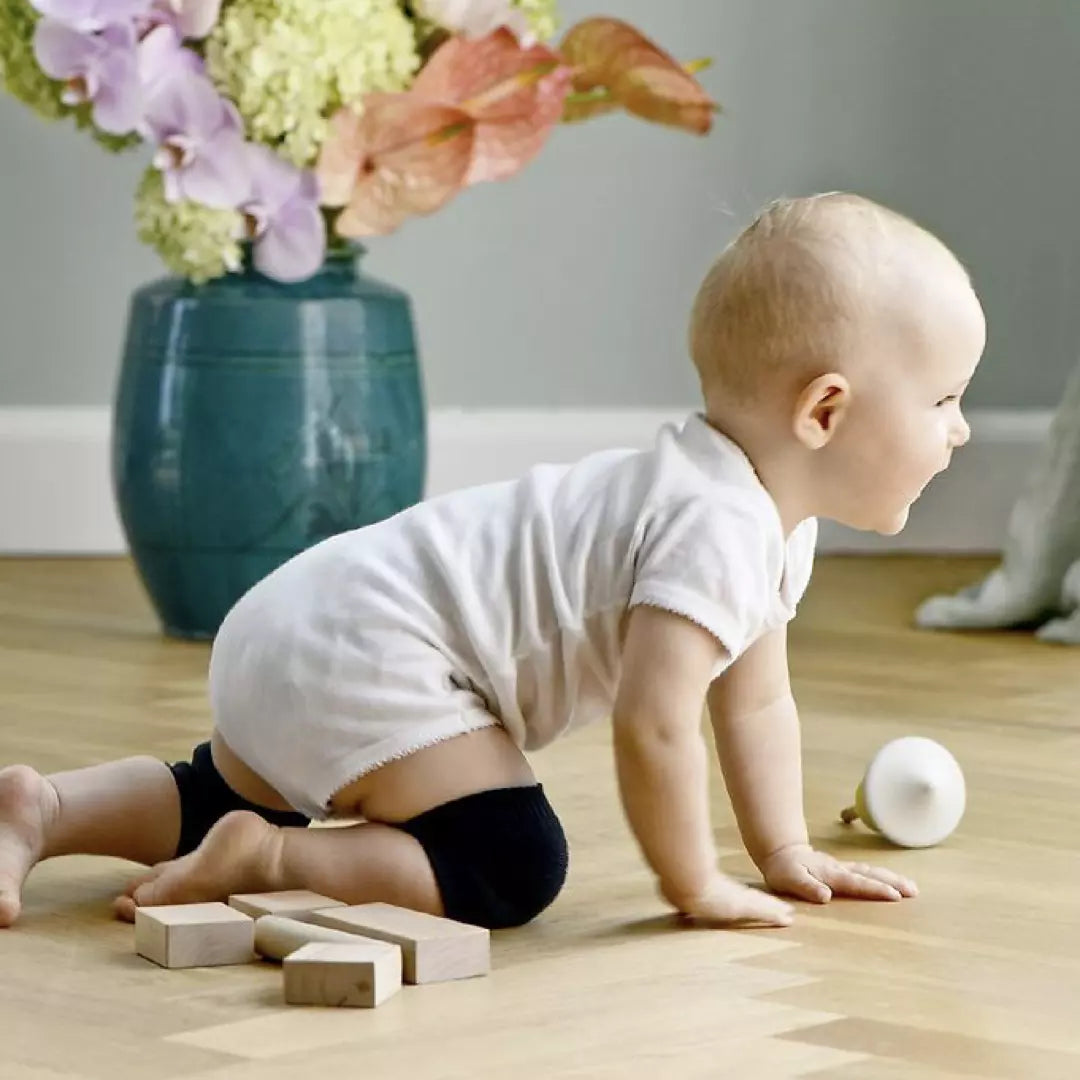 De gratis meegeleverde set kniebeschermers voor baby's en kleine kinderen in de kleur grijs wordt gedragen door een kruipend jongetje.