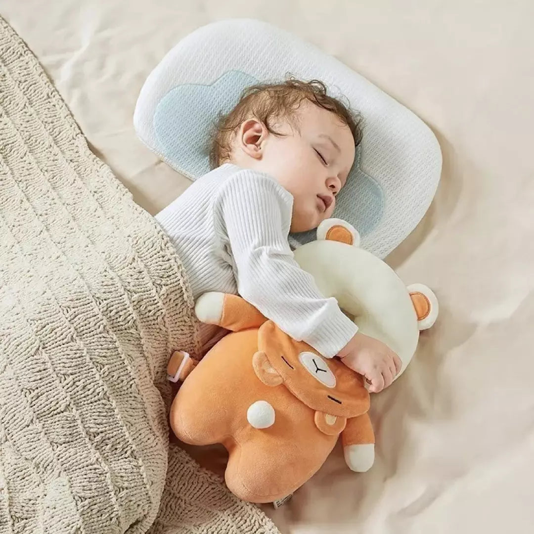 Het baby hoofdbeschermingskussen wordt vastgehouden door een jongetje dat ligt te slapen. Hij heeft het valkussen naast zich liggen als een knuffel. Dit baby valkussen biedt perfecte bescherming en heeft verstelbare riemen.