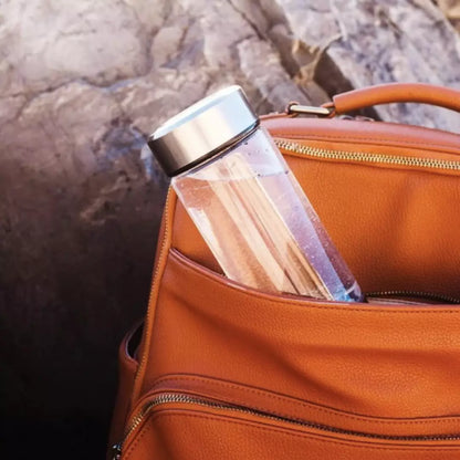 De zilveren HydroRefresh waterstof fles 2.0 zit in een oranje handtas. Dit laat zien hoe compact en draagbaar de hydrogen waterstof fles is.