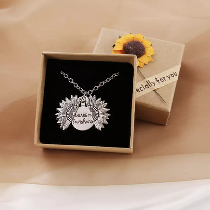 De zilveren variant van de 'You are my Sunshine' ketting wordt gedragen door een model. De ketting is geopend en je ziet de mooie boodschap. De ketting zit in de cadeauverplakking en de verpakking is geopend. 