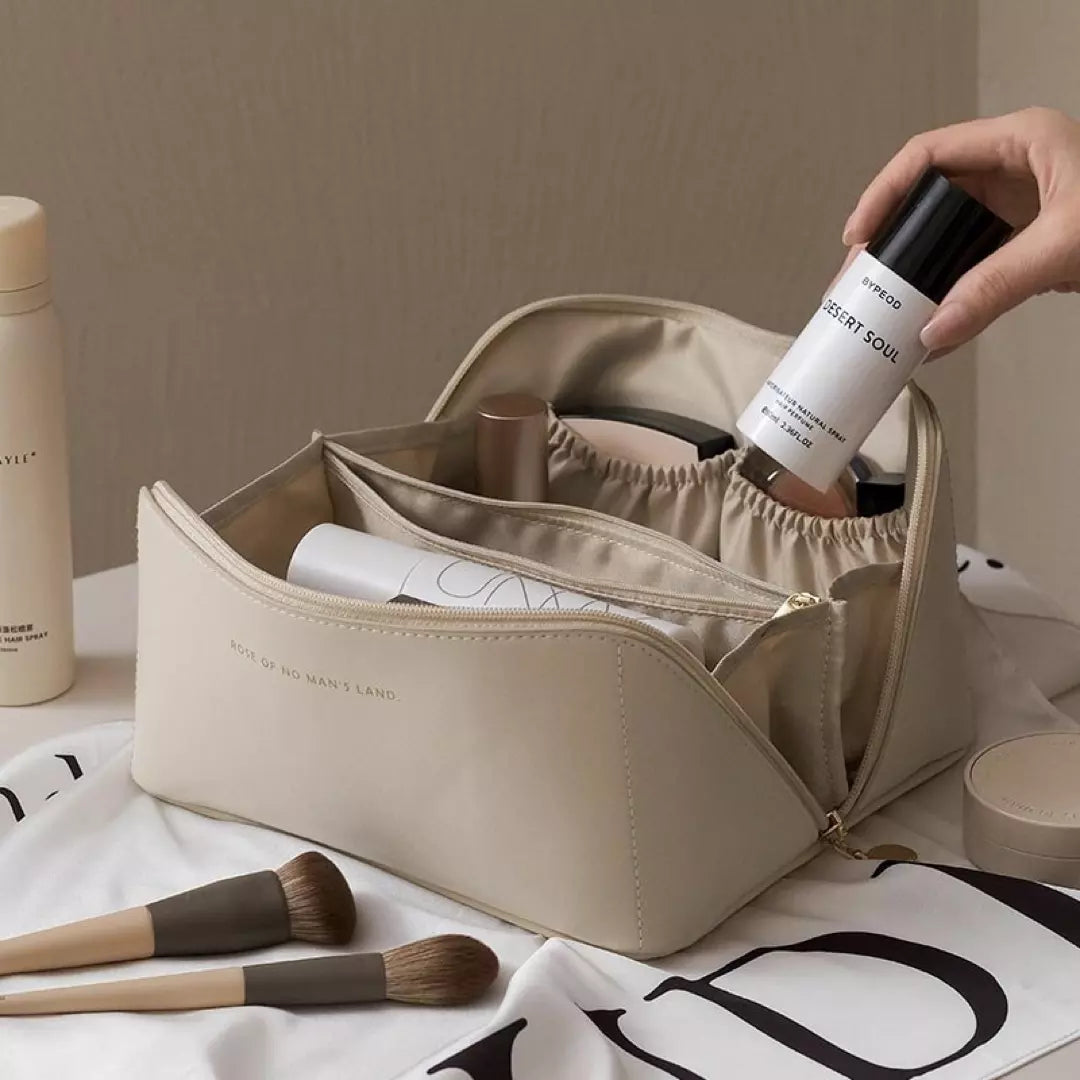 Een beige kleurige make-up toilettas gevuld met make-up artikelen.