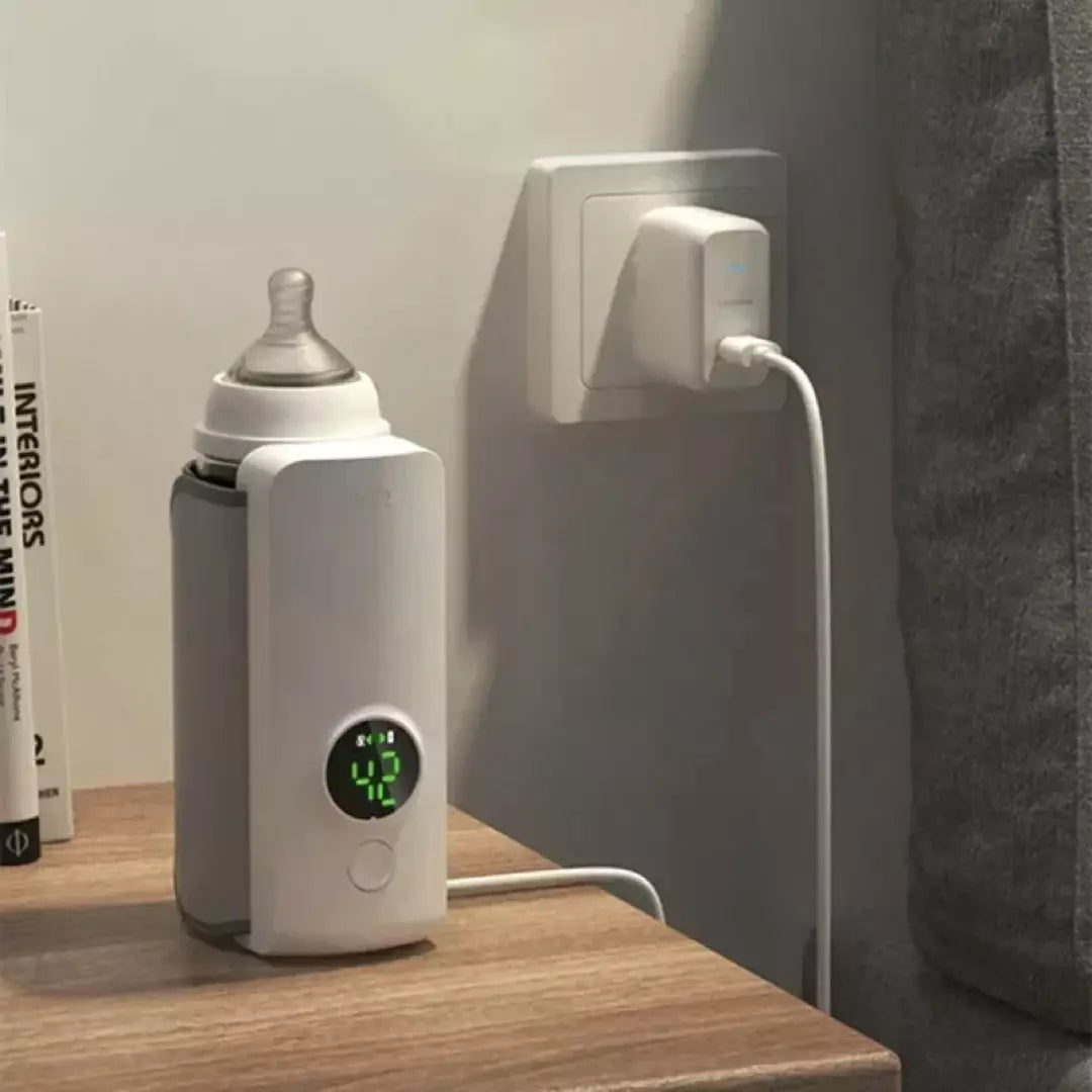 De oplaadbare flessenwarmer in de kleur wit. De flessenwarmer wordt op dit moment opgeladen via de USB kabel en er zit een flesje in de oplaadbare flessenwarmer.