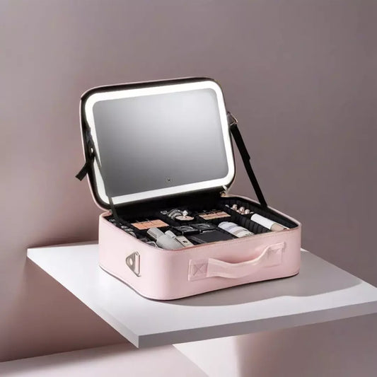 De roze variant van de beste make-up koffer voor thuis en op reis wordt afgebeeld. De make-up spiegel met verlichting staat aan en de make up koffer is opengeklapt en gevuld met make up borstels en andere make up producten.