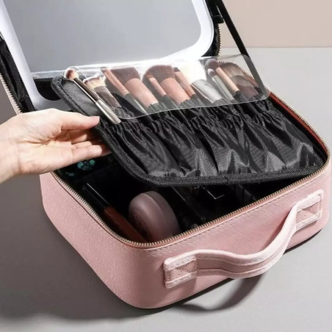 De roze variant van de beste make-up koffer voor thuis en op reis wordt afgebeeld. Een dame pakt het uitneembare compartiment met make up borstels op om te laten zien dat de make up koffer met make up spiegel meerdere vakken heeft. 