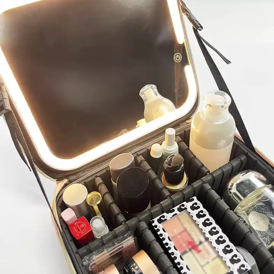 De zwarte variant van de beste make-up koffer voor thuis en op reis wordt afgebeeld. De make up koffer is gevuld met make up producten en de make up spiegel met verlichting staat aan.