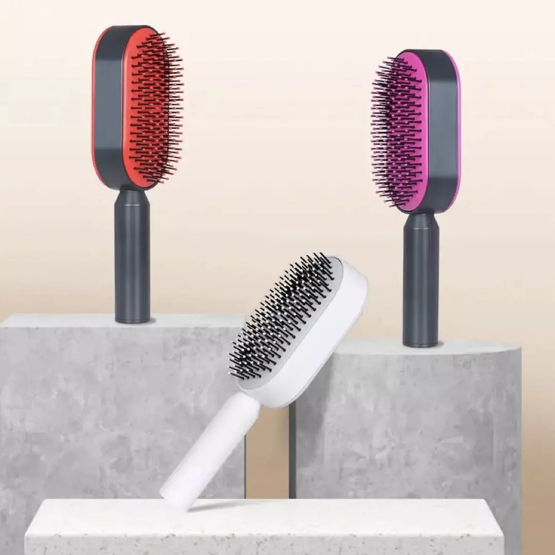 De rode, paarse en witte variant van de ZenTangle zelfreinigende haarborstels zijn weergegeven. Naast elkaar op een marmer plateau.  Je haarborstel schoonmaken kost vanaf nu geen enkele moeite meer.
